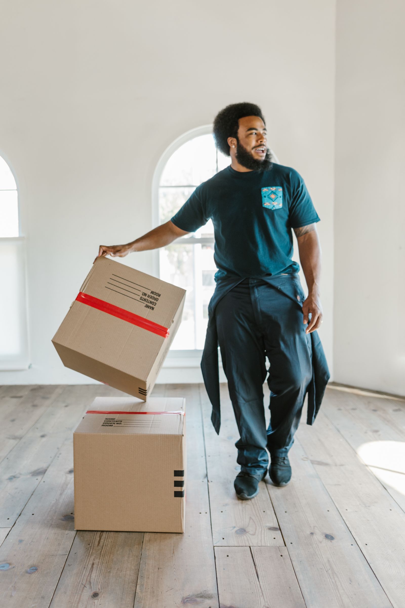 Mover lifting a cardboard box in an empty room